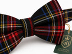 A black plaid bow tie with red, blue, yellow, and white stripes, featuring a green 'Glenorn Heritage' brand tag on a white background.