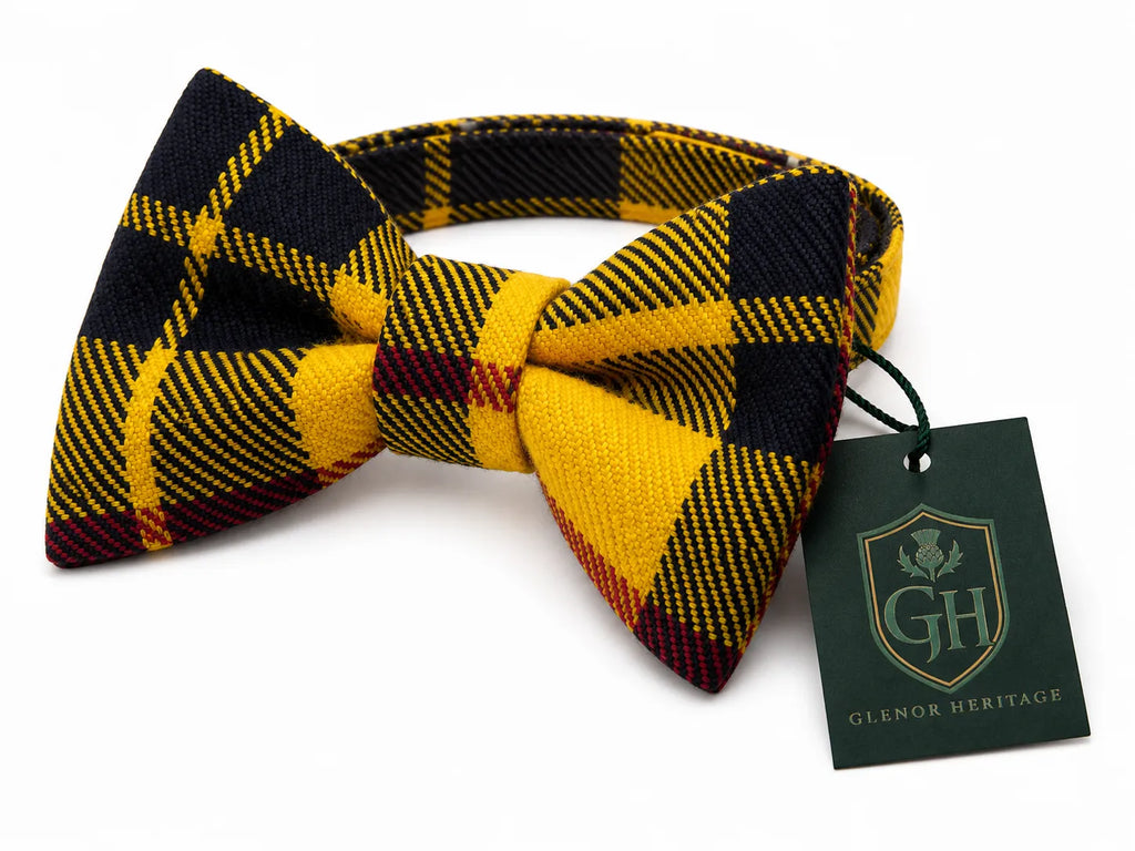A pre-tied bow tie with a yellow, black, and burgundy tartan plaid pattern, shown with a dark green 'Glenor Heritage' brand tag on a white background.