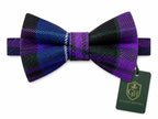 A pre-tied bow tie with a purple, black, and blue tartan plaid pattern, shown with a dark green brand tag on a plain white background.