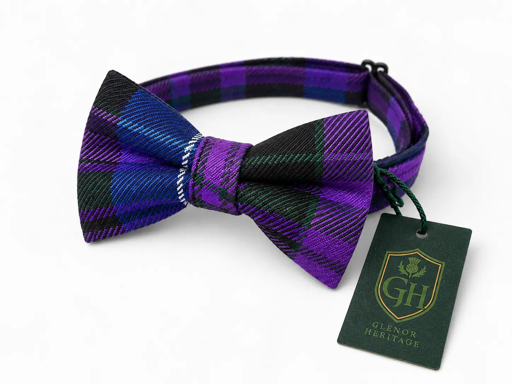 A purple, black, and blue tartan plaid bow tie with its matching neck strap, featuring a green brand tag from Glenor Heritage, on a white background.